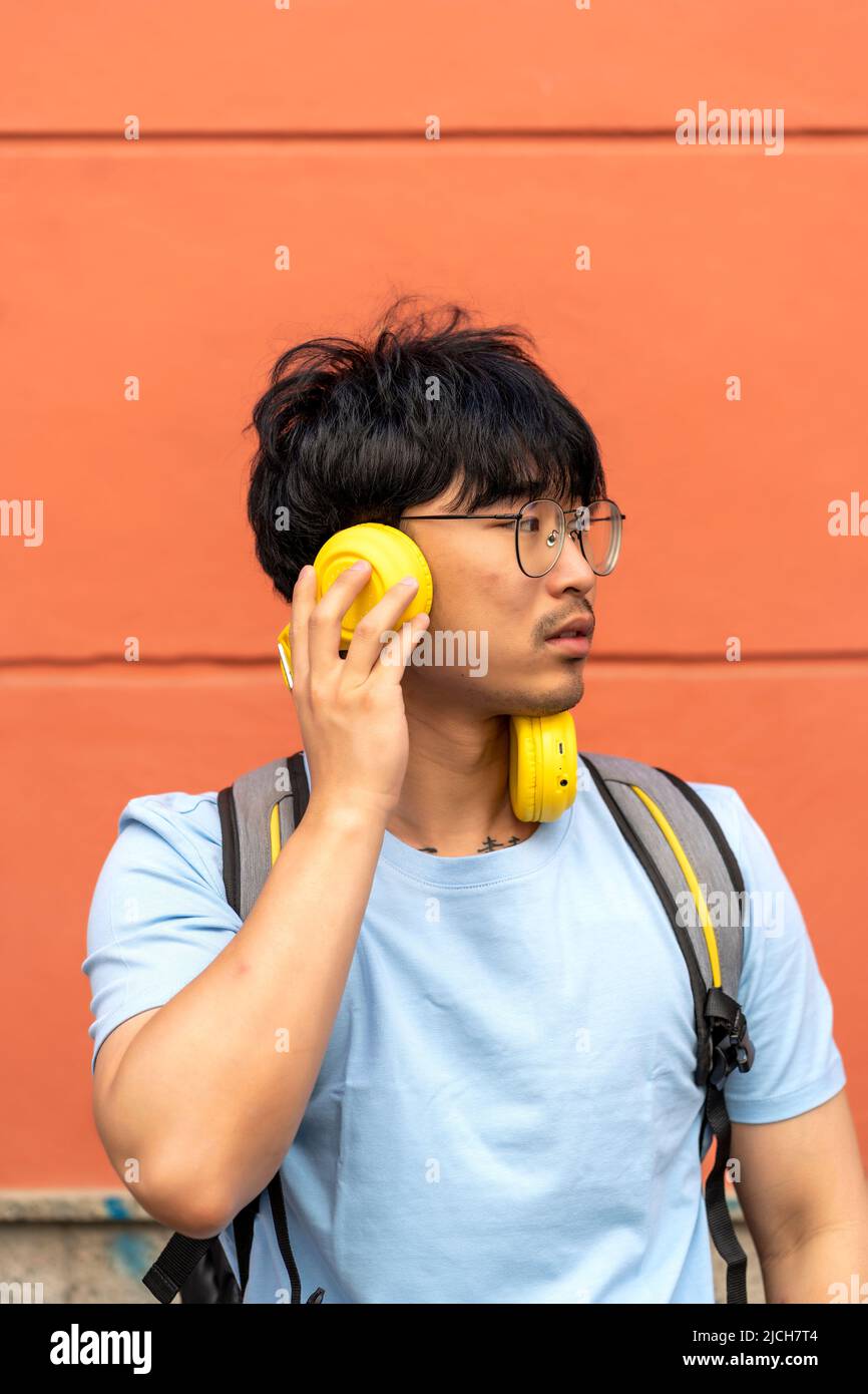 asiatischer Mann, der Musik von seinen Kopfhörern hört Stockfoto