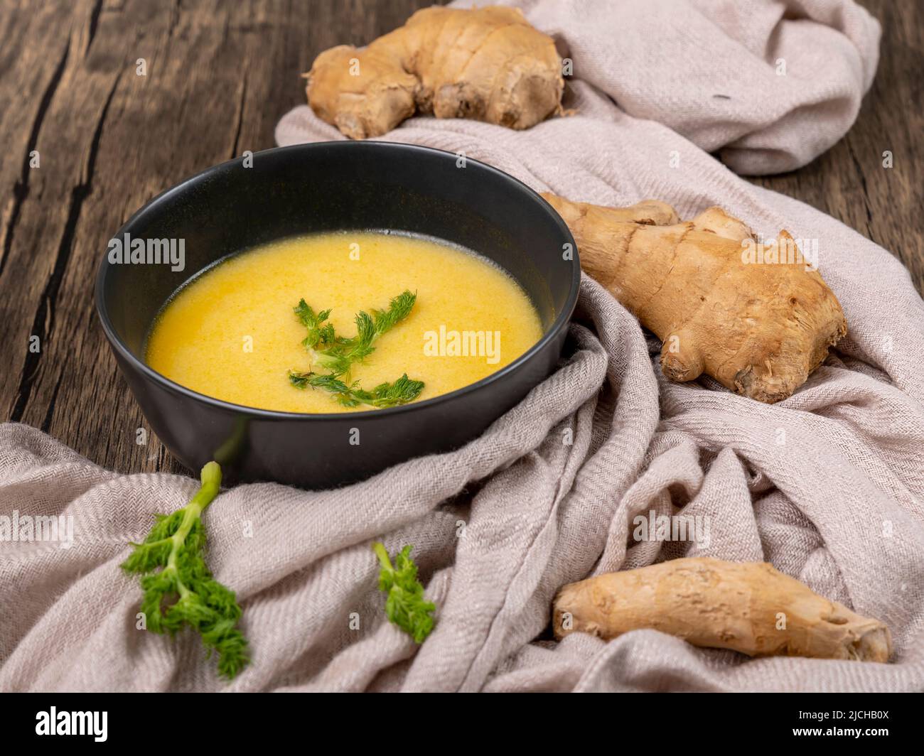Gelbe Kürbis-, Karotten-, Ingwer- und Wildfenchelsuppe in einer dunklen Schüssel Stockfoto