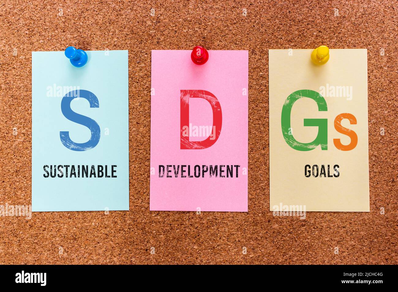 Konzept 3 Buchstaben Schlüsselwort SDGs (Sustainable Development Goals), auf bunten Aufklebern auf einem Korkbrett angebracht. Stockfoto