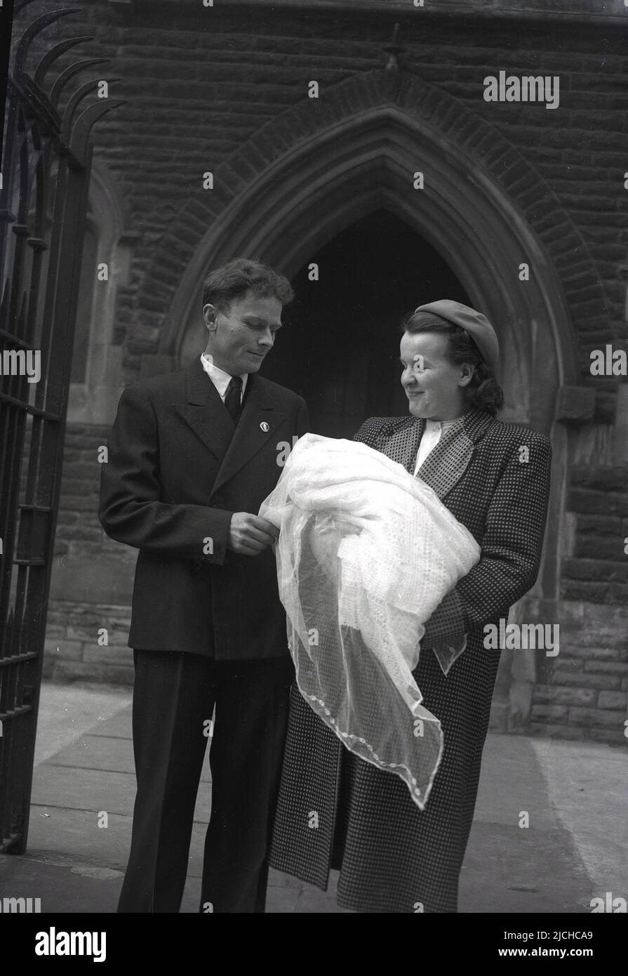1940s, historische, stolze Eltern, die mit ihrem gerade getauften Baby vor der Kirche, England, Großbritannien, stehen. Stockfoto