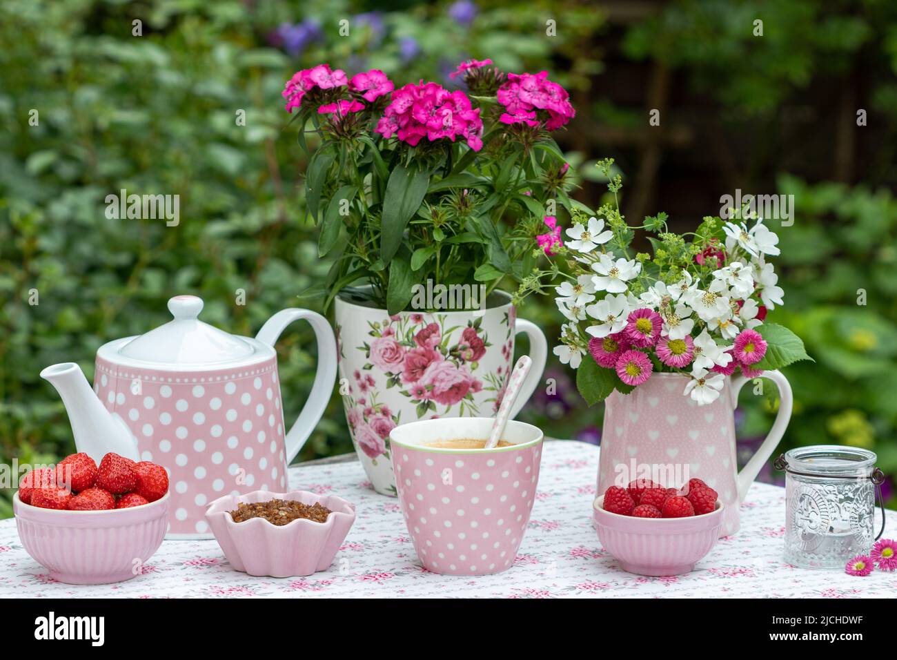 Tischdekoration mit einer Tasse Kaffee, frischen Beeren und Sommerblumen Stockfoto