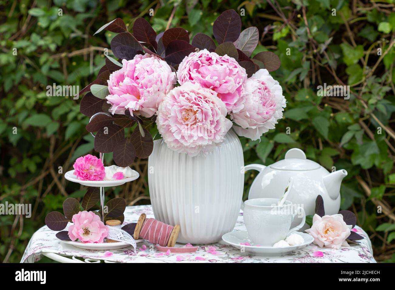 Romantische Tischdekoration mit Blumenstrauß aus Pfingstrosen und Porzellan Stockfoto