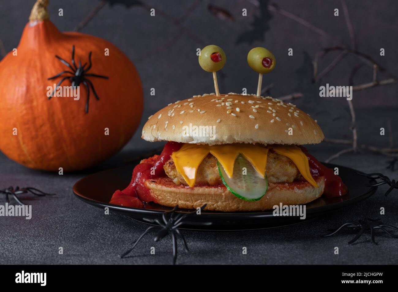 Lustige Monster Chicken Burger mit Toast Käse, Ketchup und Gurke. Kreatives Halloween-Essen Stockfoto