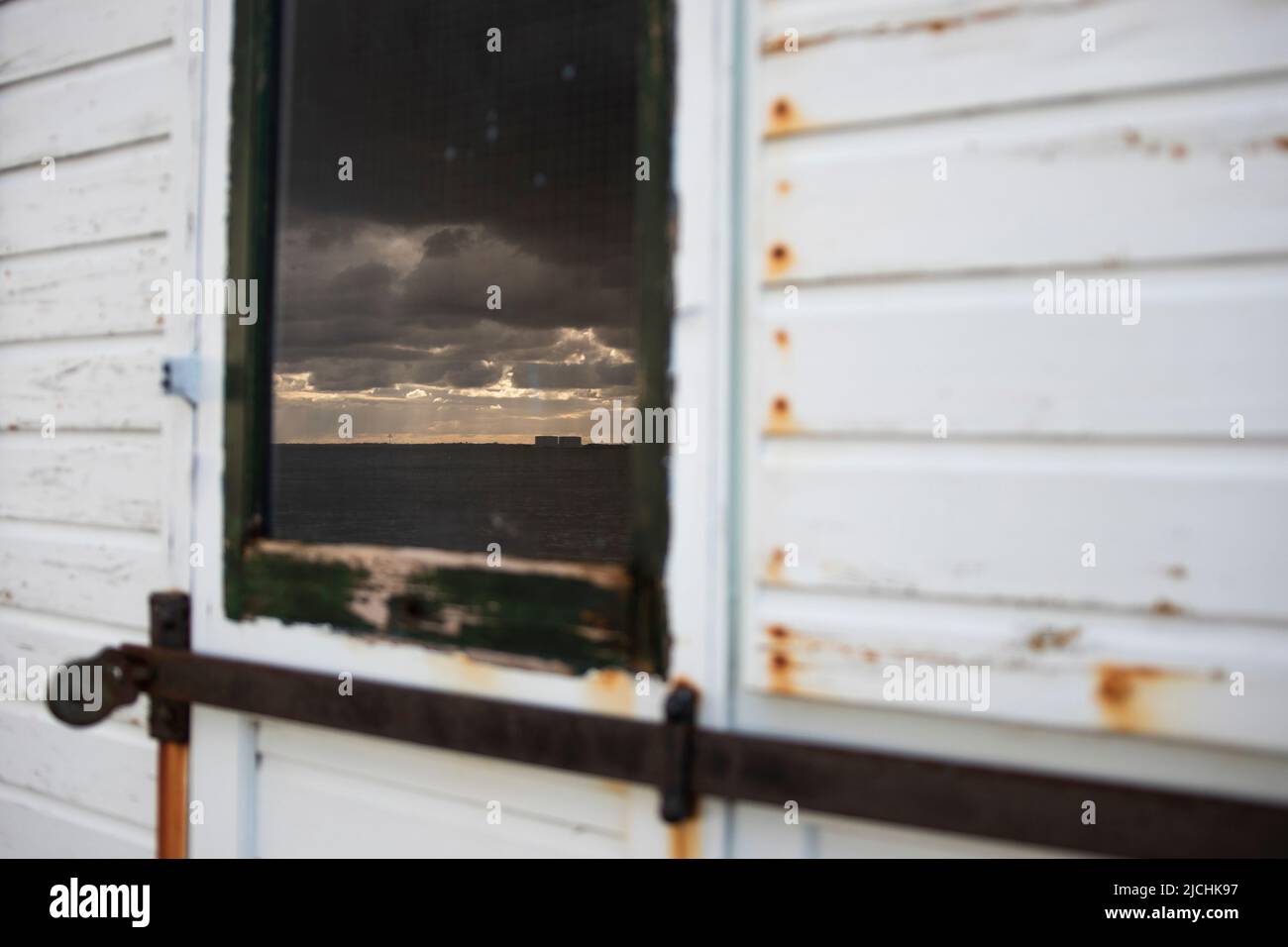 Das Kernkraftwerk Bradwell spiegelte sich im Fenster einer Strandhütte in West Mersea, Essex, Großbritannien, wider Stockfoto
