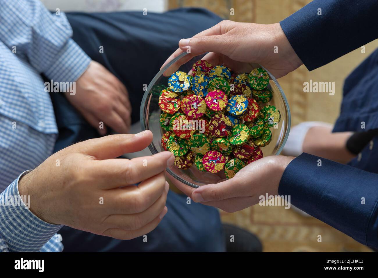 Iyi-Bayramlar- oder eid-mubarak-Konzept. Türkische Traditionen in islamischen Festen. Ein älterer Mann pflückte eine Schokolade aus einer Schüssel. Eid al adha oder fitr Conce Stockfoto