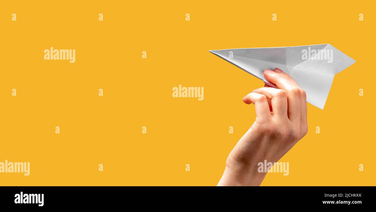 Banner mit Frau Hand werfen Origami-Flugzeug auf orangefarbenem Hintergrund. Freiheit, Startkonzept. Papierfaltung Kunst. Platz für Text. Hochwertige Fotos Stockfoto