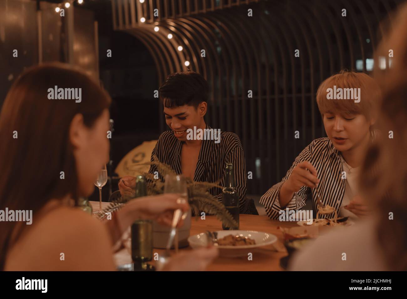 Junge asiatische Freunde essen und genießen gemeinsam das Abendessen im Restaurant im Freien. Freundschaft und Wiedersehensfeier Stockfoto