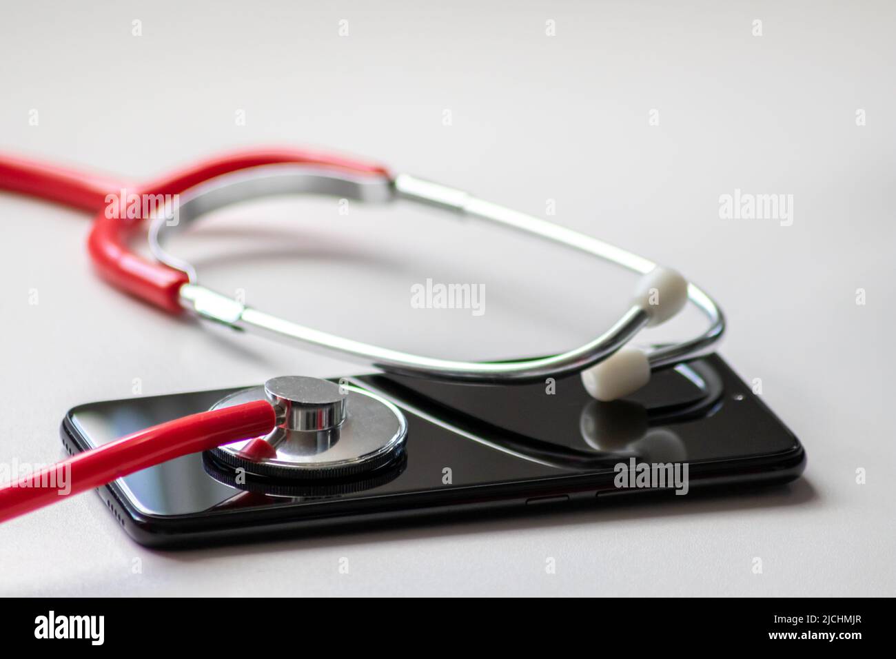 Das rote Stethoskop auf dem schwarzen Smartphone stellt Gesundheitsakten und digitale Patientenakten mit mobilen Geräten für die digitale Diagnose von Ärzten dar Stockfoto
