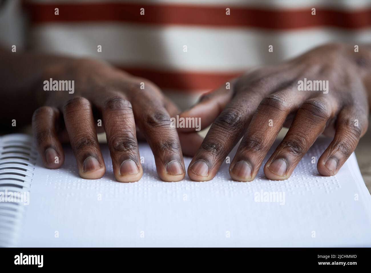 Makroaufnahme eines blinden afroamerikanischen Mannes, der Buch in Braille liest, zugängliches Informationskonzept, Kopierraum Stockfoto