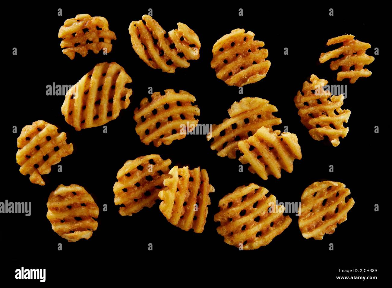 Draufsicht auf appetitlich geschnittene Kartoffelchips mit knuspriger Kruste auf schwarzem Hintergrund Stockfoto