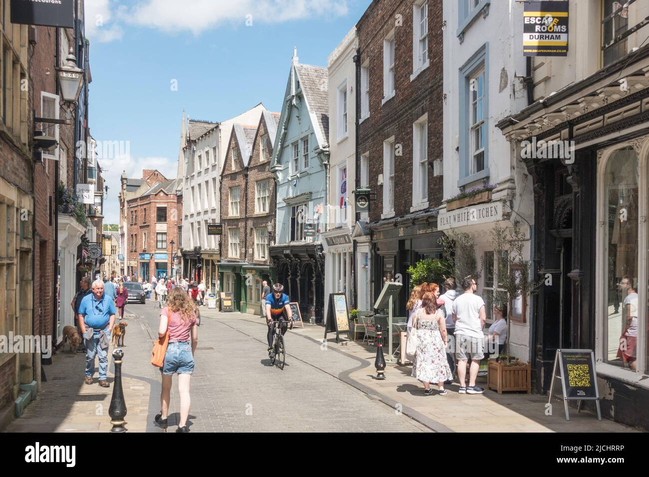 Spaziergänger und ein Mann, der entlang der Saddler Street im Stadtzentrum von Durham, England, Großbritannien, radelt Stockfoto