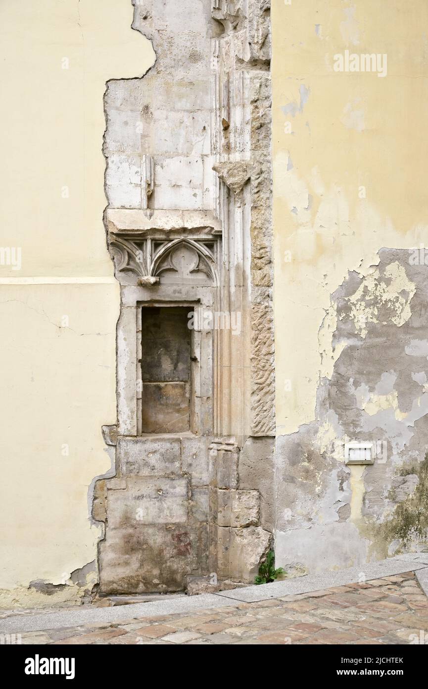 Ein altes Fenster in Prag, das seine gotischen Wurzeln zwischen verblassenden Farbschichten und Gips zeigt. Stockfoto