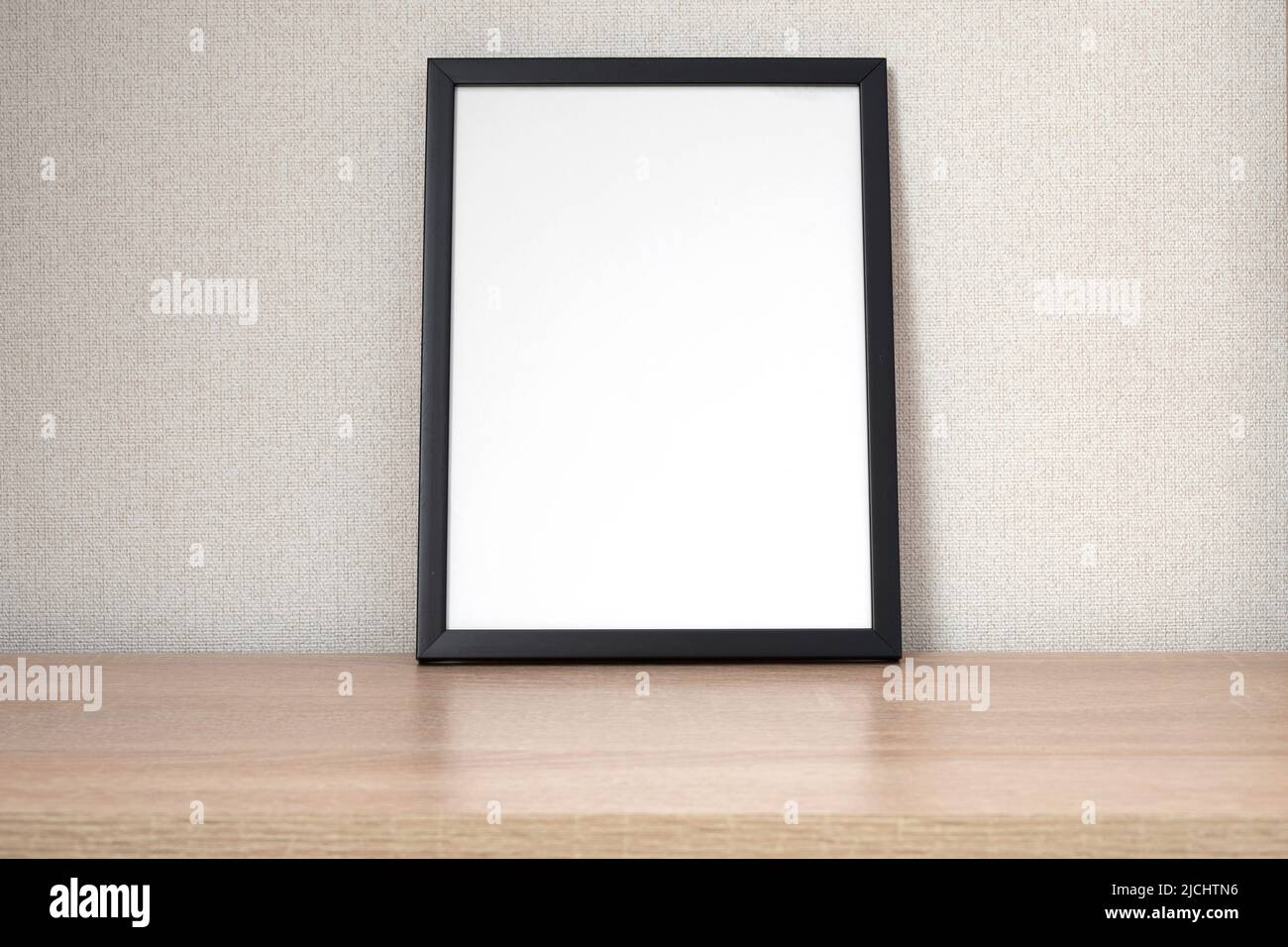 Schwarzer Fotorahmen mit leerem weißen Platz auf Holzregal, Schreibtisch. Modell, Vorlagenraum für Text Stockfoto