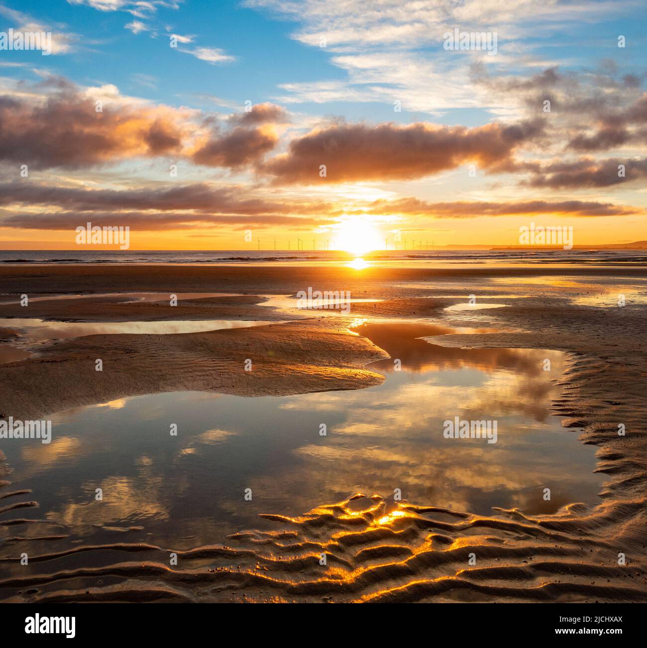 Atemberaubender Sonnenaufgang mit Spiegelungen auf dem Küstenpfad von England am Strand von Seaton Carew, Nordostengland, Großbritannien. Stockfoto