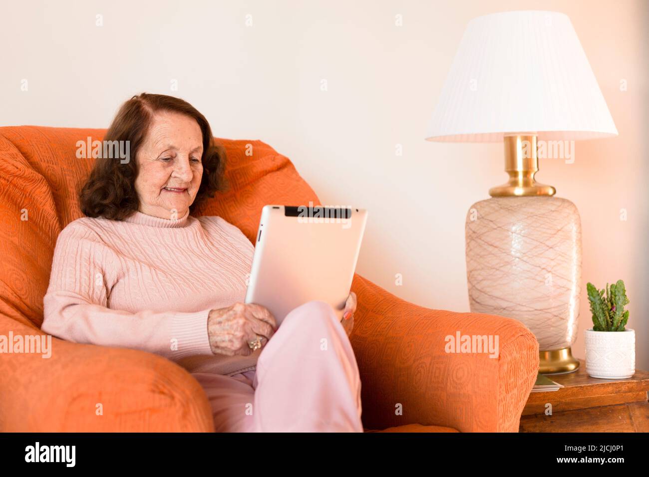 Ältere kaukasische Frau, die zu Hause ein digitales Tablet verwendet. Konzept der Technologie und Senioren. Platz für Text. Stockfoto