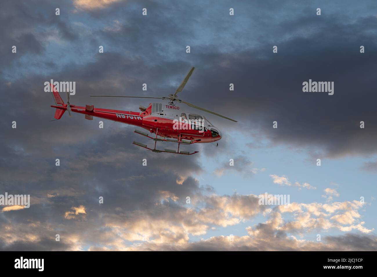 Skagway, Alaska, USA - 20. Juli 2011: Taiya Inlet über Chilkoot Inlet. Rot-grauer TEMSCO Hubschrauber gegen dunkle Wolkenlandschaft mit blauen Flecken. Stockfoto