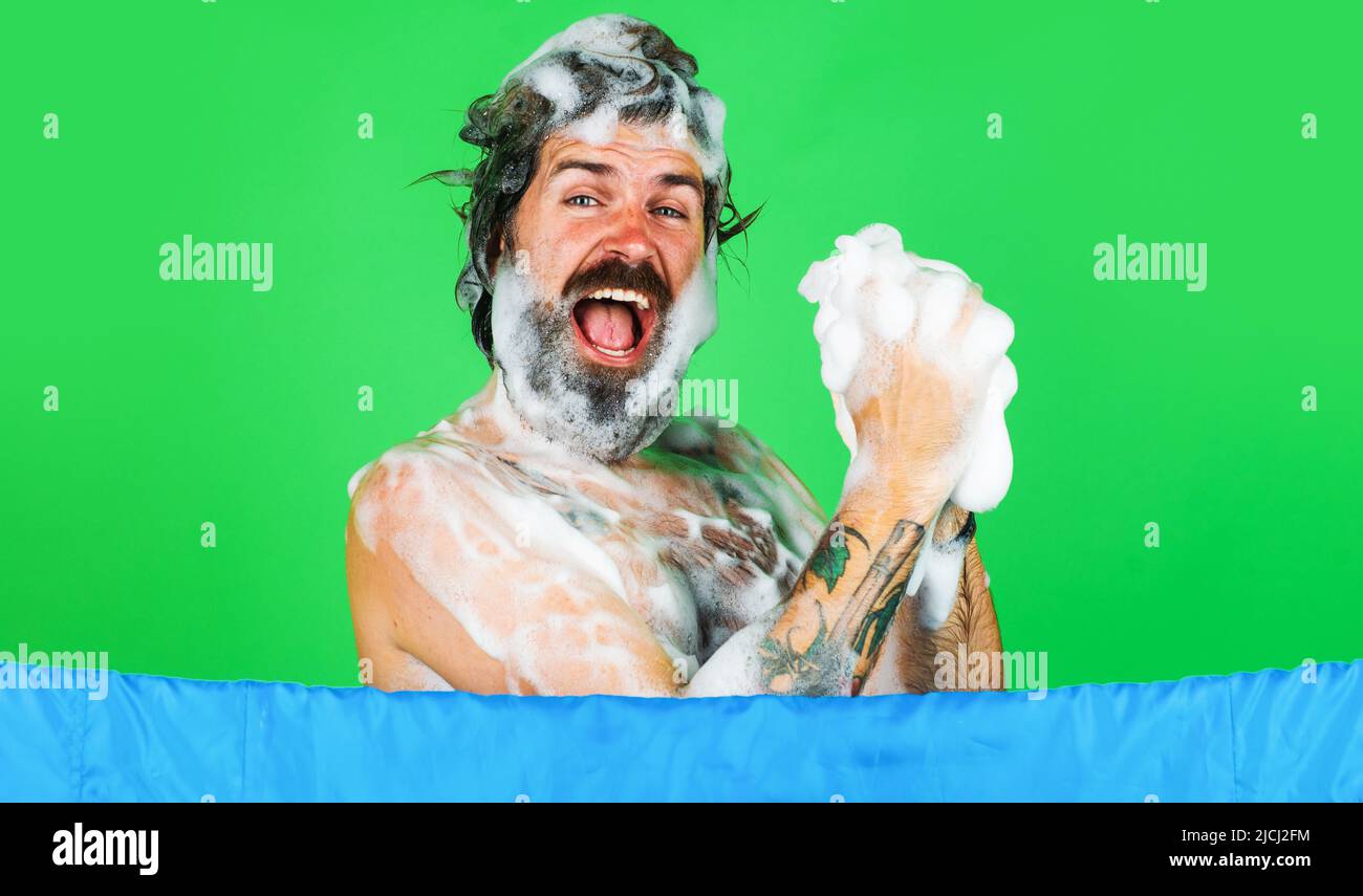 Happy man wasche den Körper mit feuchtigkeitsspendendem Gel in der Dusche. Morgendliche Routine. Bärtiger Kerl mit Schaum auf dem Kopf. Stockfoto