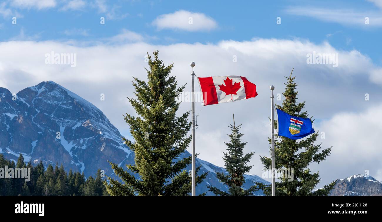Nationale Flagge von Kanada und Flagge von Alberta. Natürliche Berge und Bäume Landschaft im Hintergrund. Stockfoto