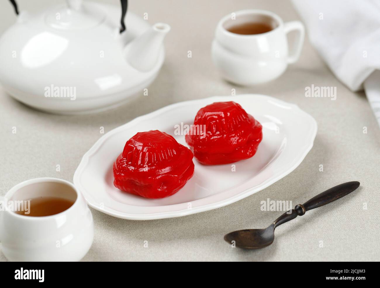 Angku Kueh oder Kue Ku, Red Tortoise Cake mit Mungbean Paste Füllung, beliebt als Kue Thok. Serviert mit Tee Stockfoto