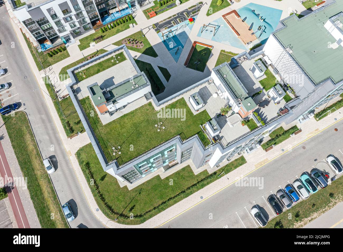 Modernes Appartementhaus mit grünem Grasboden auf Flachdach. Drohnenfoto von oben. Stockfoto