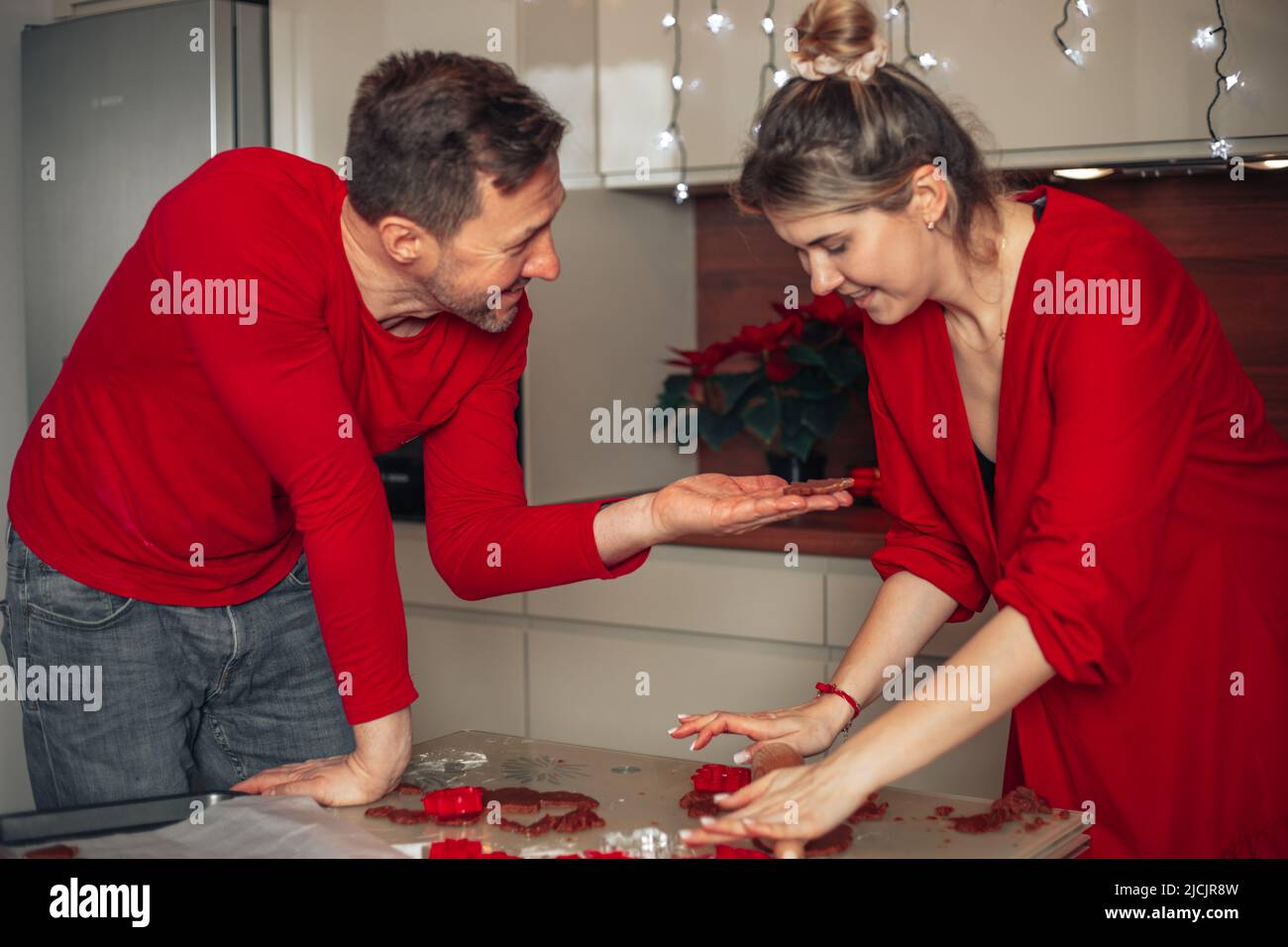 Mann und Frau haben Spaß beim Reden in der Küche. Viel zu backen, Kekse für Weihnachten, Weihnachtsmomente, glückliches Paar. Kochen zu Hause. Stockfoto