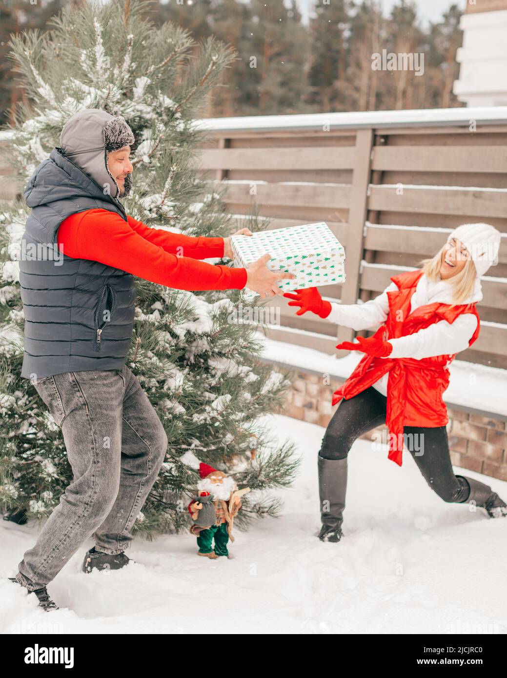 Glückliches Paar in der Liebe haben Spaß mit Geschenkbox in der Nähe Winter schneebedeckten Tannenbaum. Frau und Mann haben einen guten Sinn für Humor Stockfoto