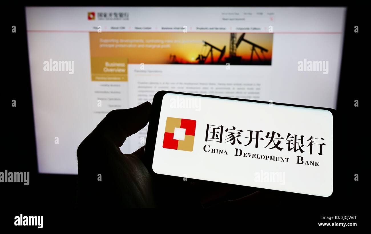 Person mit Mobiltelefon und Logo der China Development Bank (CDB) auf dem Bildschirm vor der Webseite. Konzentrieren Sie sich auf die Telefonanzeige. Stockfoto