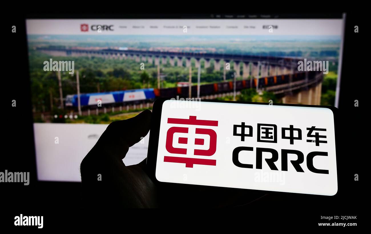 Person, die ein Mobiltelefon mit dem Logo des chinesischen Unternehmens CRRC Corporation Limited auf dem Bildschirm vor der Unternehmenswebseite hält. Konzentrieren Sie sich auf die Telefonanzeige. Stockfoto