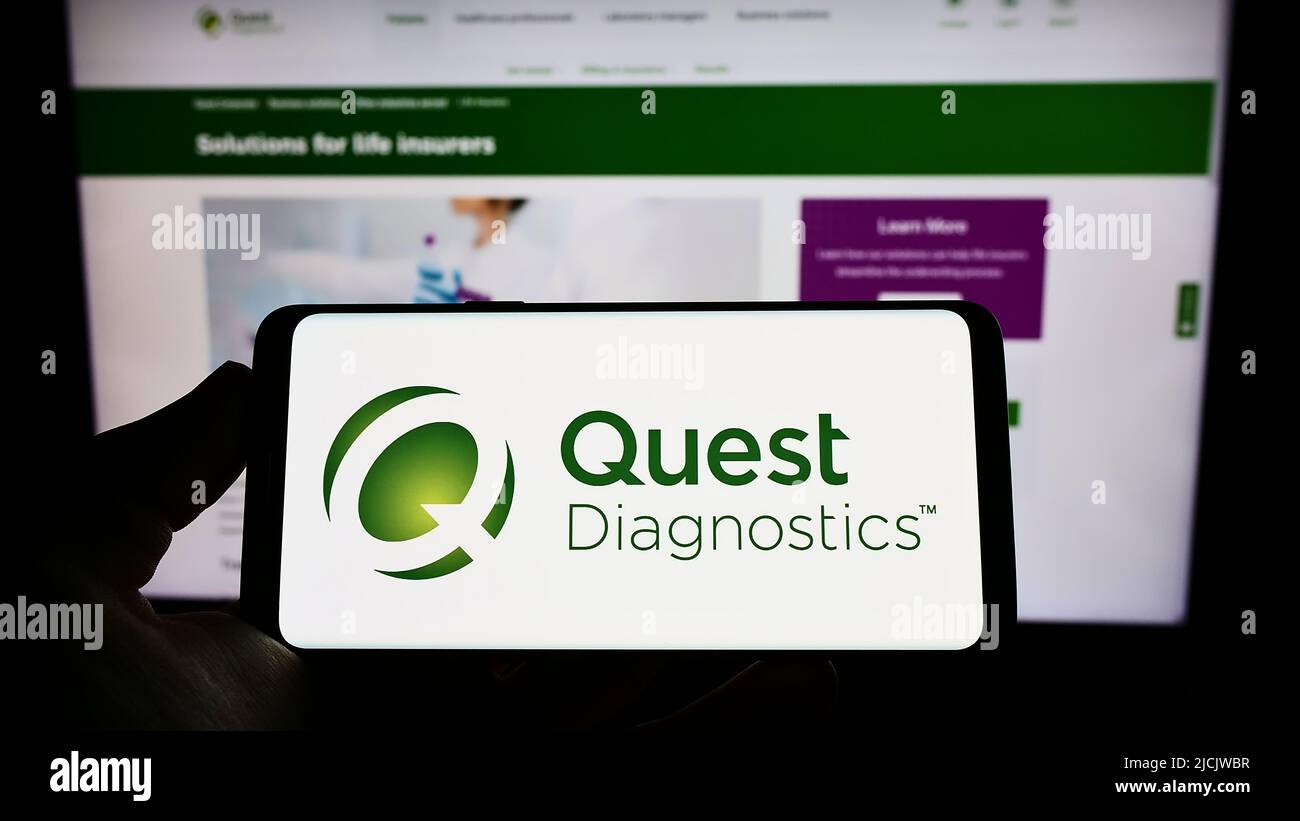 Person, die das Smartphone mit dem Logo des US-Laborunternehmens Quest Diagnostics Inc. Auf dem Bildschirm vor der Website hält. Konzentrieren Sie sich auf die Telefonanzeige. Stockfoto