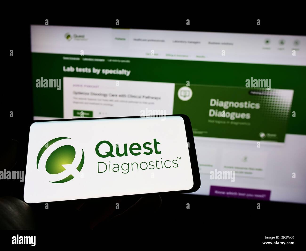 Person mit Mobiltelefon und Logo des amerikanischen Laborunternehmens Quest Diagnostics Inc. Auf dem Bildschirm vor der Webseite. Konzentrieren Sie sich auf die Telefonanzeige. Stockfoto