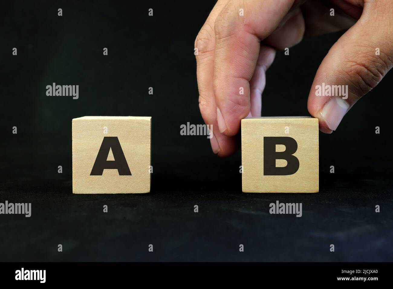 Plan B oder Backup- und Verfügbarkeitsplan im Geschäftskonzept. Hand wählt B gegen A in Holzblöcken auf dunkelschwarzem Hintergrund. Stockfoto