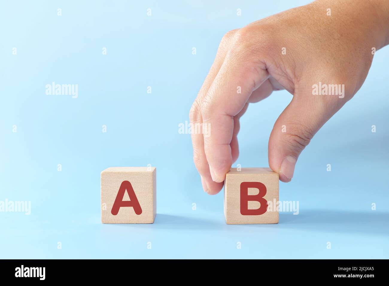 Plan B oder Backup- und Verfügbarkeitsplan im Geschäftskonzept. Hand wählt B gegen A in Holzblöcken auf blauem Hintergrund. Stockfoto