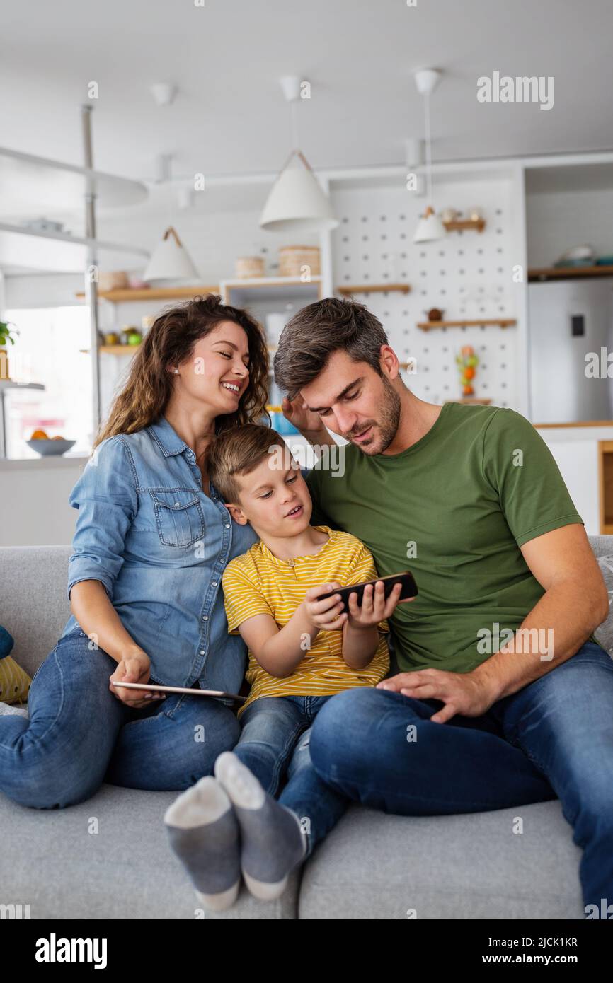 Glückliche Familie, die digitale Technologie-Dekore für das Spielen von Filmen verwendet, um zu Hause zu entspannen. Stockfoto