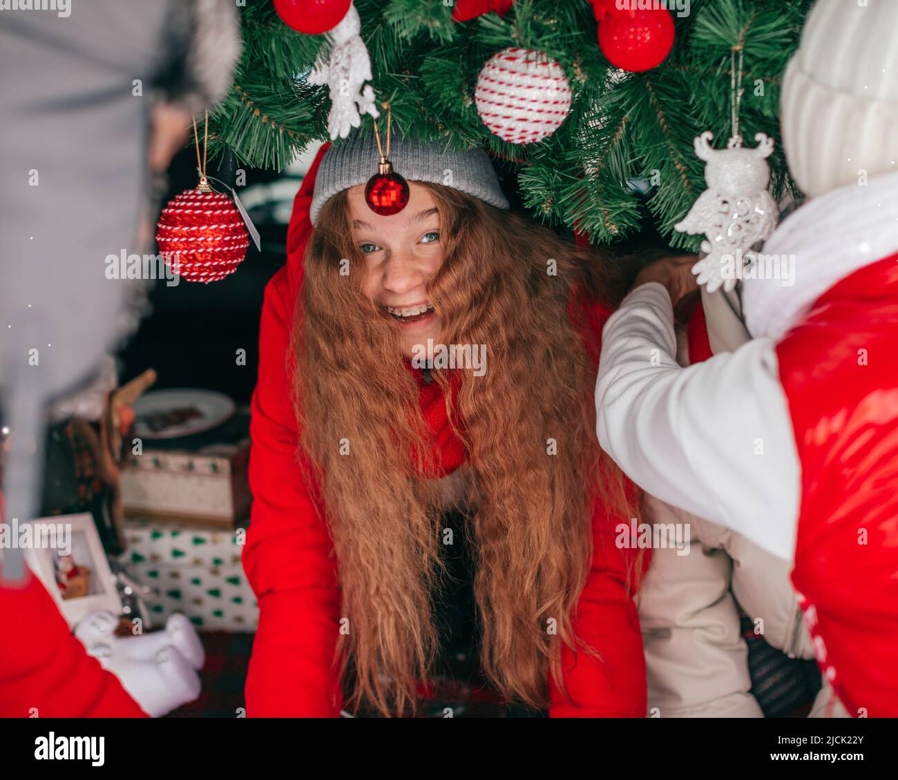 Schöne Teenager-Mädchen 13 Jahre mit langen roten Haaren lachen unter Weihnachtsdekoration im Kofferraum Stockfoto