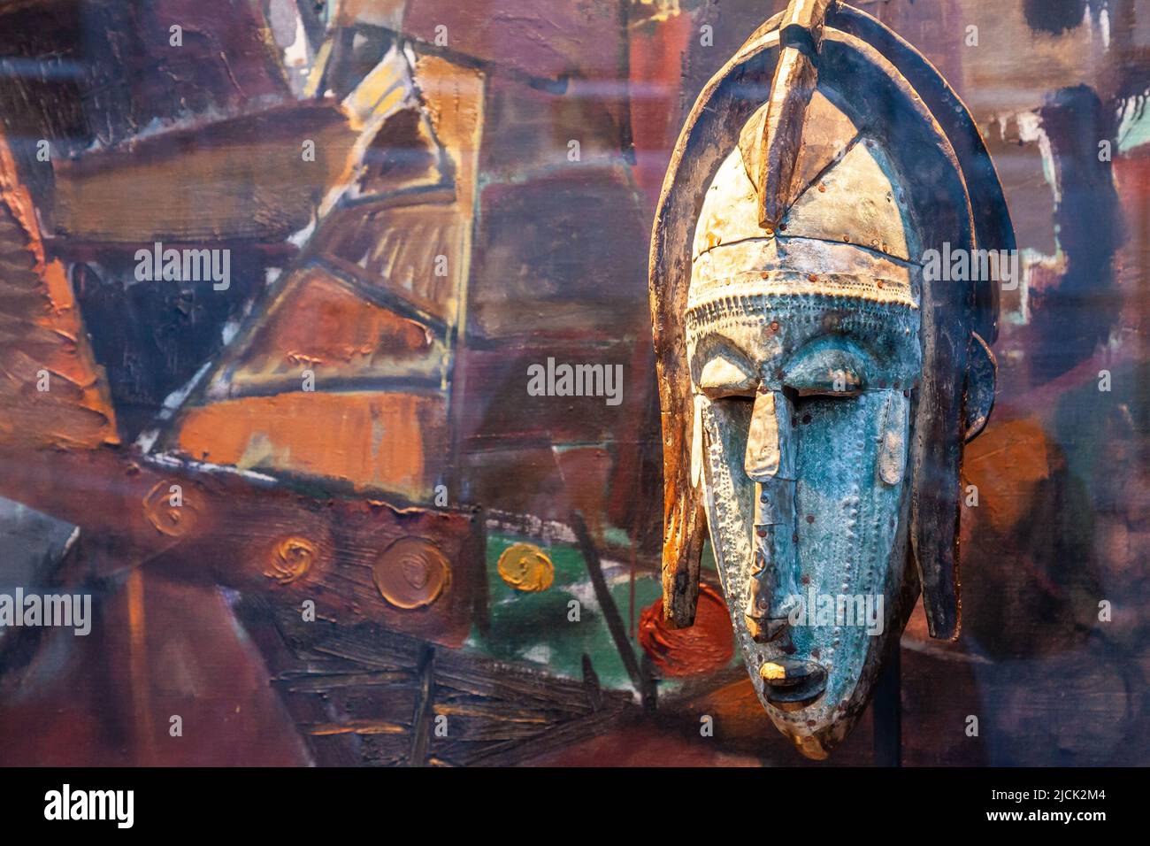 Alte Maske im Fenster eines Antiquitätenladens ausgestellt. Farbenfroher Hintergrund. Brüssel. Stockfoto