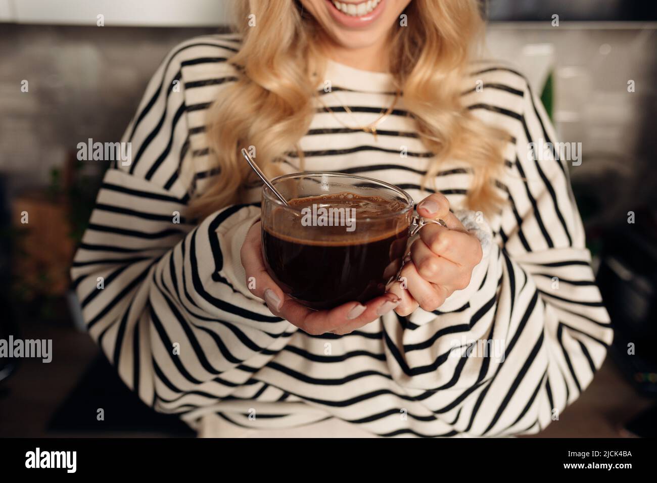 Junge unkenntliche Frau lächelt weit und hält eine Tasse Kaffee Stockfoto