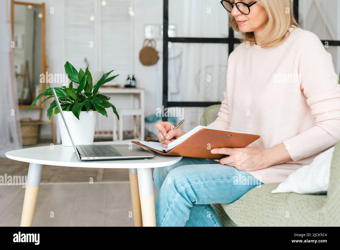 Nette Erwachsene ältere Frau in einer Brille, die in ihrem Laptop-Computer arbeitet. Schöne erfahrene Frau, die in ihr Online-Banking-Investmenthandel macht Stockfoto