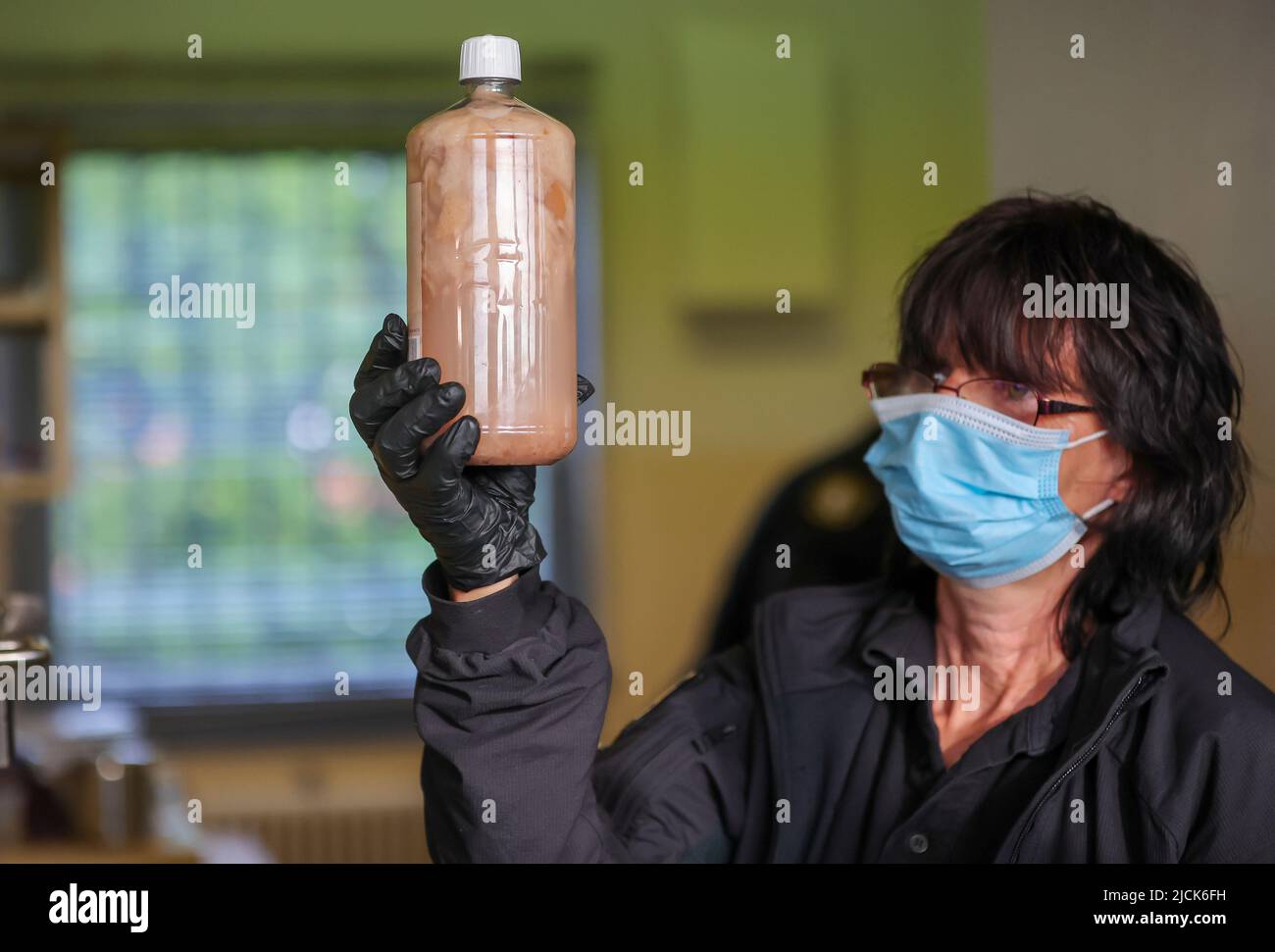 14. Juni 2022, Sachsen-Anhalt, Raßnitz: Eine Justizbeamtin des sogenannten Sondersicherheits- und Kontrolldienstes (BSRD) überreicht während einer Inspektionsmission im Jugendstrafanstalt Raßnitz (ja) eine Flasche hausgemachten Wein (Weißbrot mit Obst). Etwa 12 dieser Inspektionen werden pro Jahr in allen Haftanstalten durchgeführt. Ziel ist es, verbotene Gegenstände wie Waffen oder Speichermedien sowie Alkohol und Drogen zu finden. Foto: Jan Woitas/dpa Stockfoto