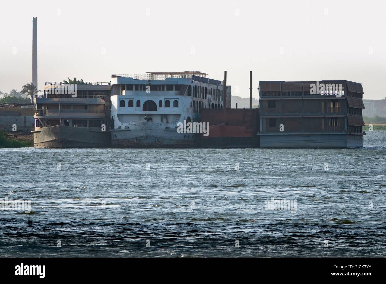 Vier verlassene Nilkreuzfahrtschiffe vertäuten und stapelten sich vom Ufer aus, wobei der Fluss im Vordergrund stand Stockfoto