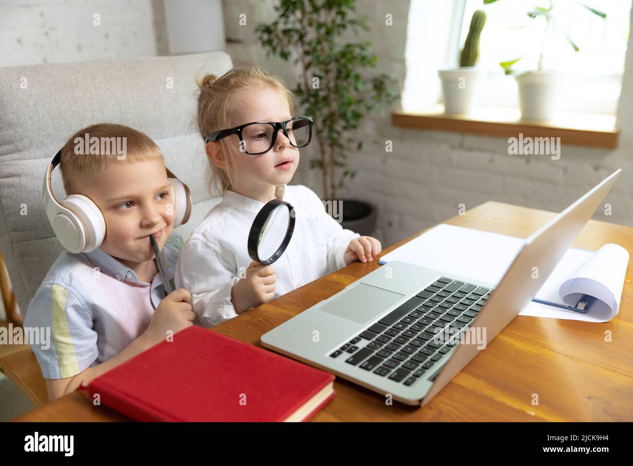 Glückliche Kinder, Bruder und Schwester sitzen zu Hause und Hausaufgaben zu Hause innen, drinnen. Online-Bildung, Kindheit, Menschen, Fernstudium und Stockfoto