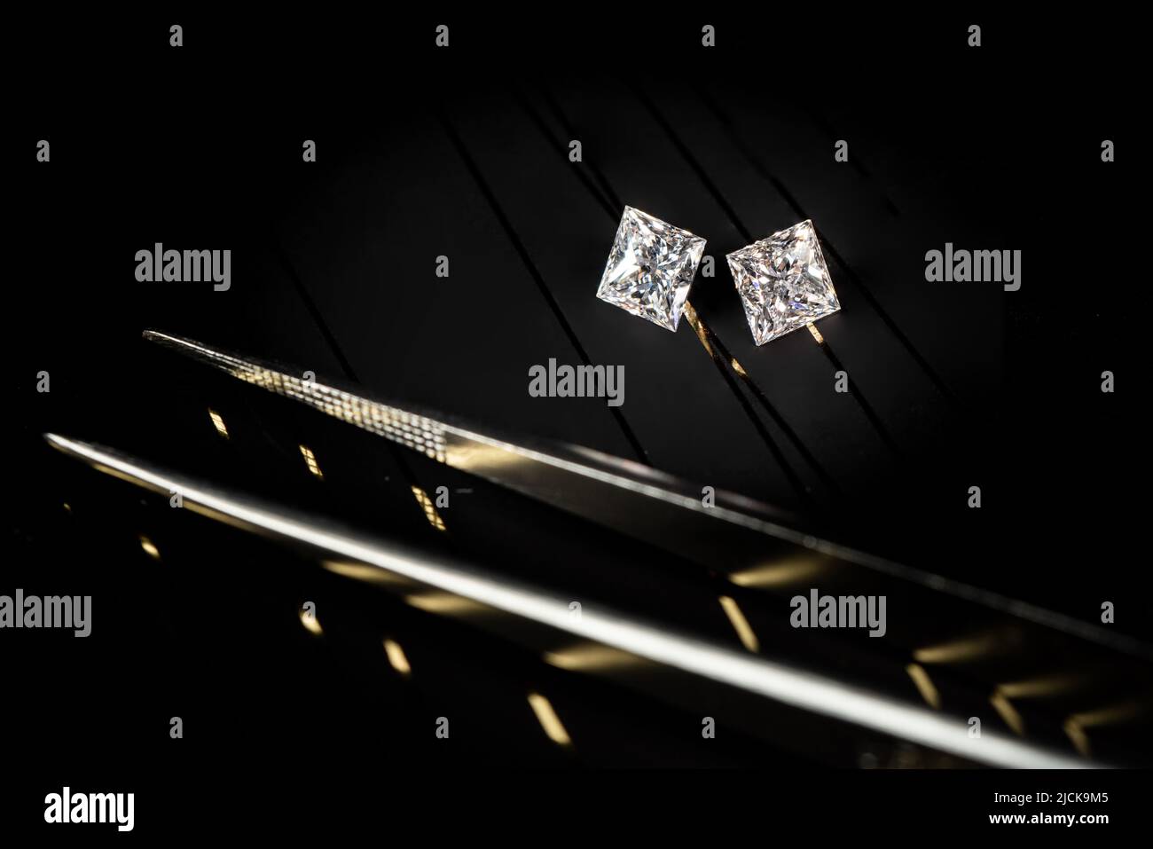 Ein Paar Prinzessschliffdiamanten, die auf schwarzem Surfaace reflektiert werden Stockfoto