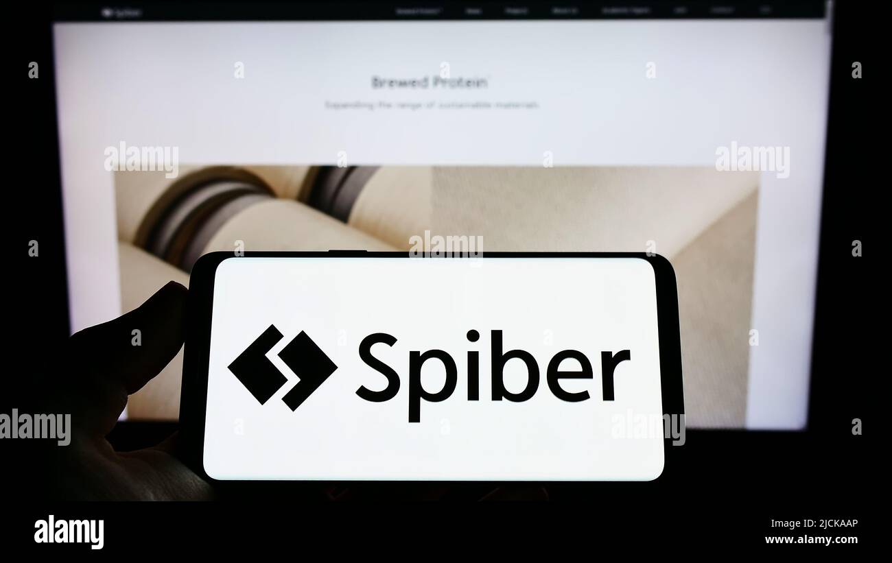 Person, die Mobiltelefon mit dem Logo des japanischen Biotechnologie-Unternehmens Spiber Inc. Auf dem Bildschirm vor der Business-Webseite hält. Konzentrieren Sie sich auf die Telefonanzeige. Stockfoto