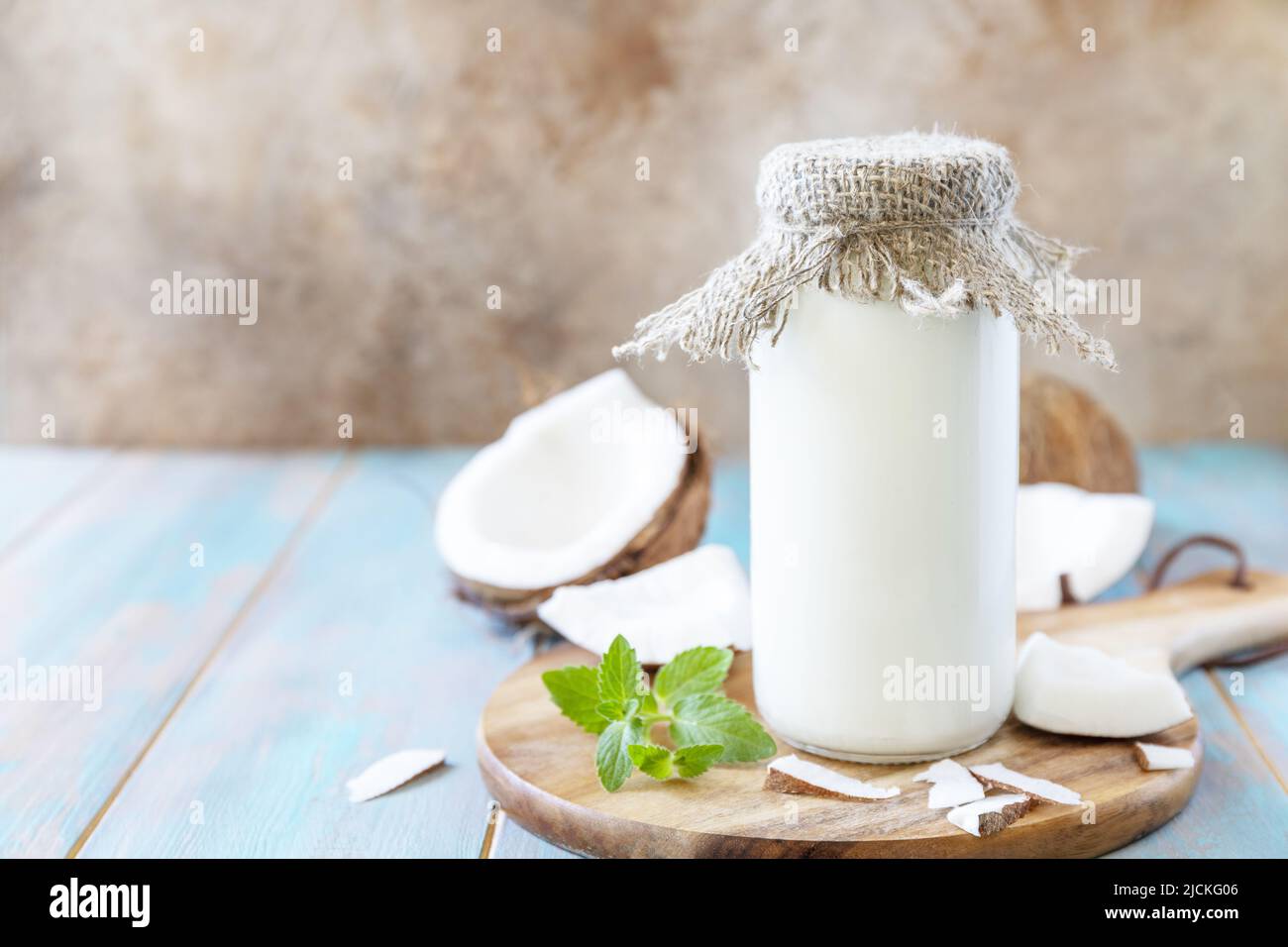 Vegane nicht milchfreie Alternativmilch, gesundheitlicher Gehalt. Bio-Kokosmilch in einer Flasche auf einem rustikalen Tisch. Speicherplatz kopieren. Stockfoto