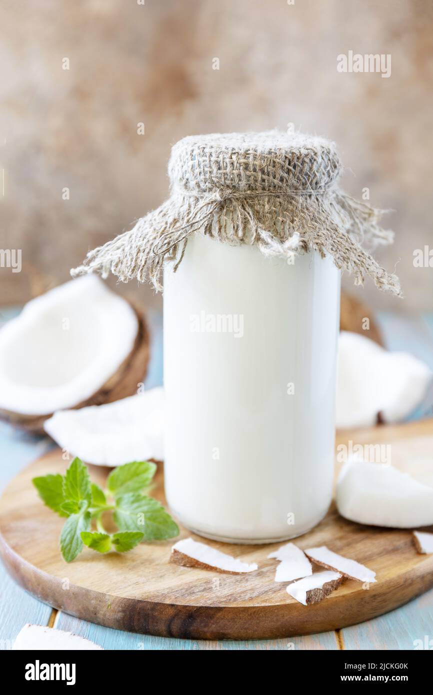 Vegane nicht milchfreie Alternativmilch, gesundheitlicher Gehalt. Bio-Kokosmilch in einer Flasche auf einem rustikalen Tisch. Stockfoto