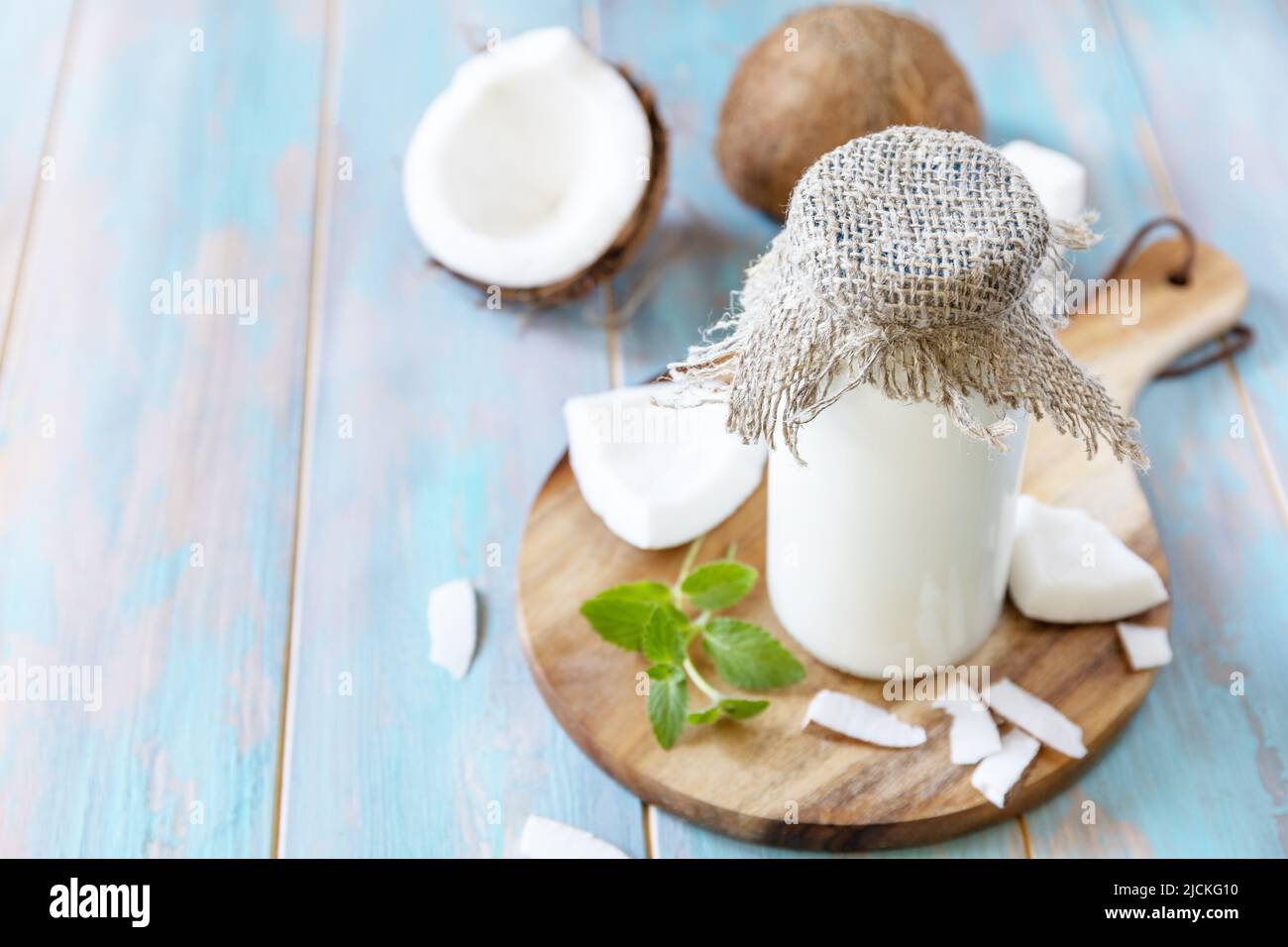 Vegane nicht milchfreie Alternativmilch, gesundheitlicher Gehalt. Bio-Kokosmilch in einer Flasche auf einem rustikalen Tisch. Speicherplatz kopieren. Stockfoto