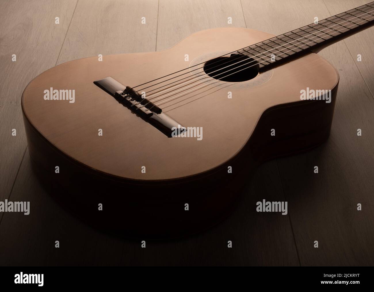 Klassischer Gitarrenkörper dramatisch isoliert aus der Nähe auf einem hellen Hintergrund. Stockfoto