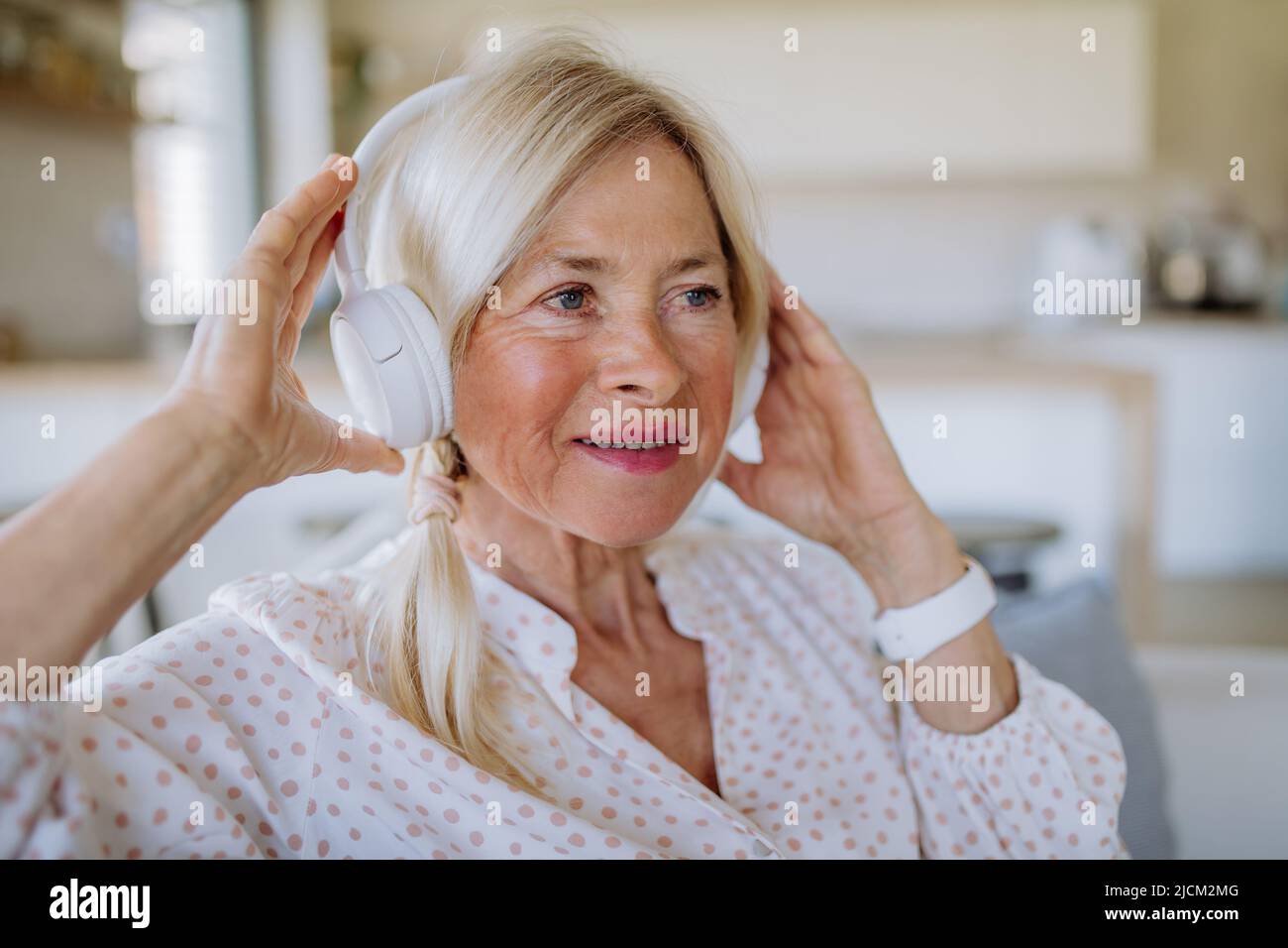 Ältere Frau mit Kopfhörern, die zu Hause Entspannungsmusik hört Stockfoto