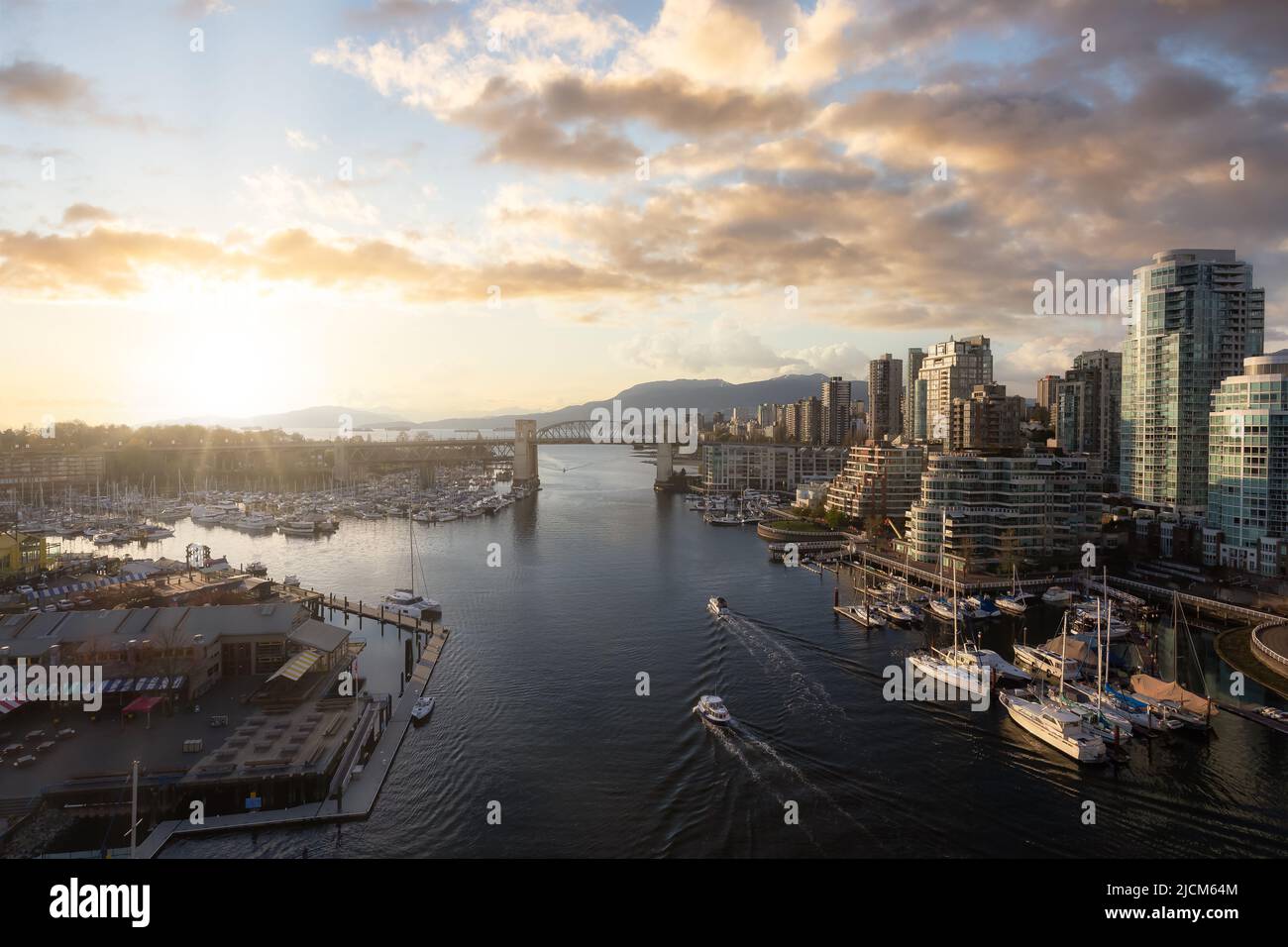 Luftaufnahme von Granville Island in False Creek mit moderner Skyline und Bergen im Hintergrund. Stockfoto