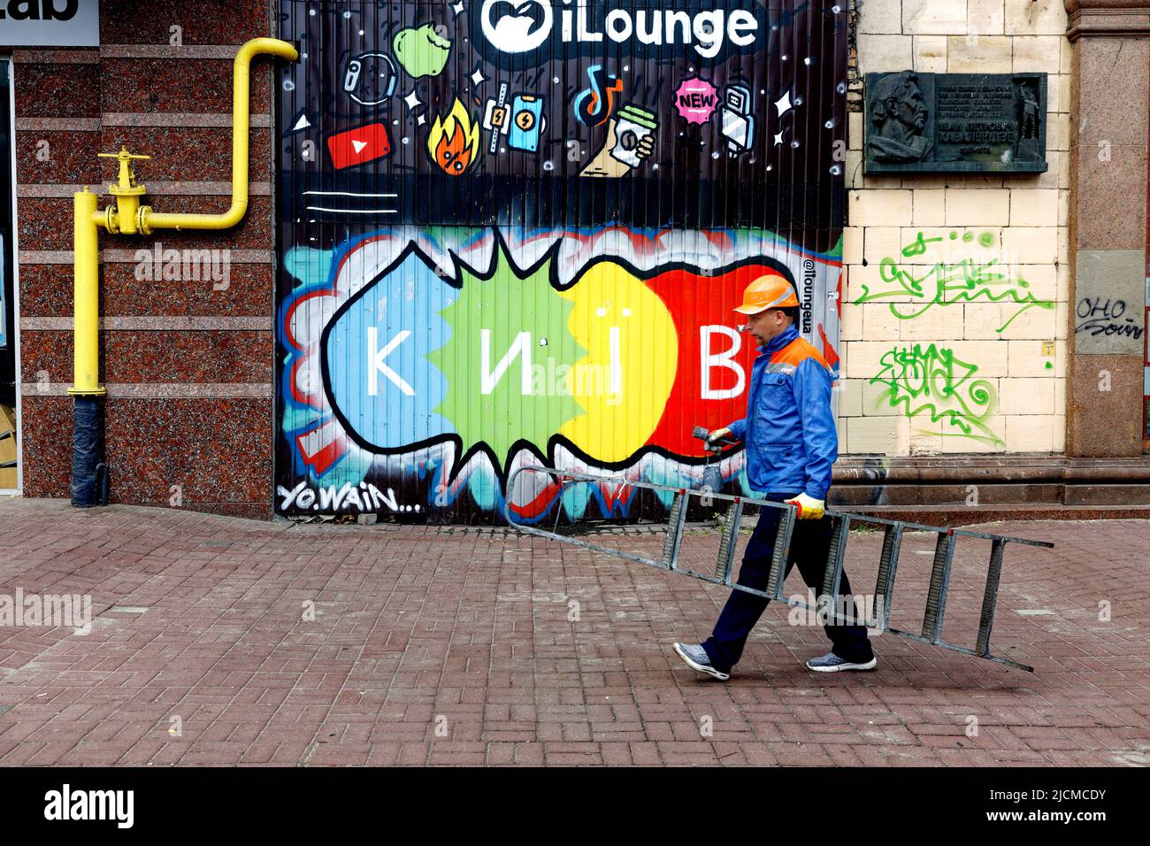 Ein Dienstmann mit Treppe geht an das Schild von Kiew.während eines Tages. Stockfoto