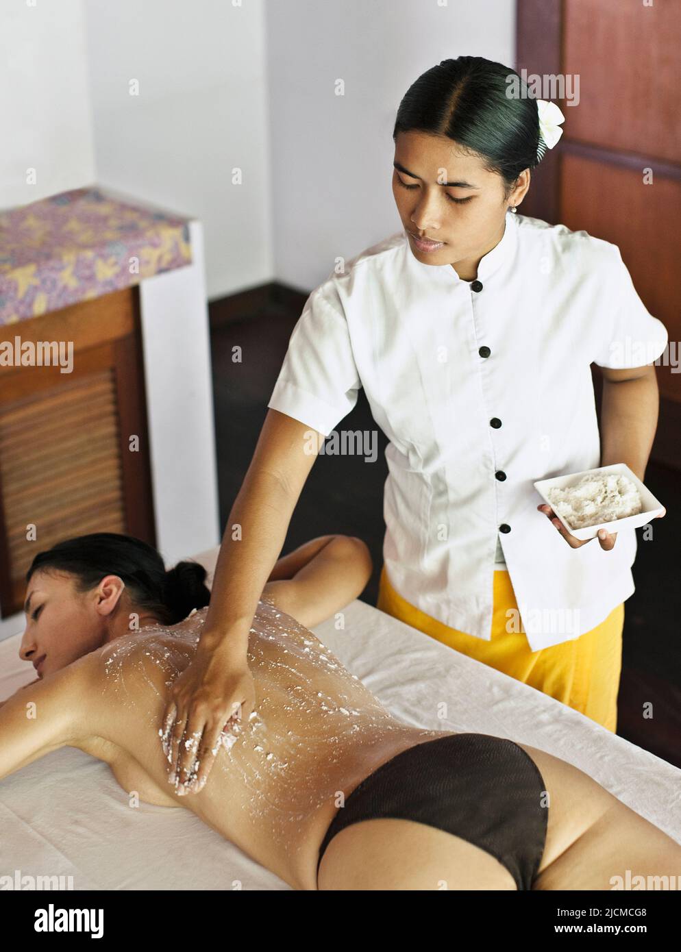 Junge Frau erhält Kokosnuss- und Reisschrubben im Ayung Spa, Ubud Hanging Gardens, Bali, Indonesien. Bei diesem Peeling handelt es sich um eine 60-minütige Peeling-Behandlung Stockfoto